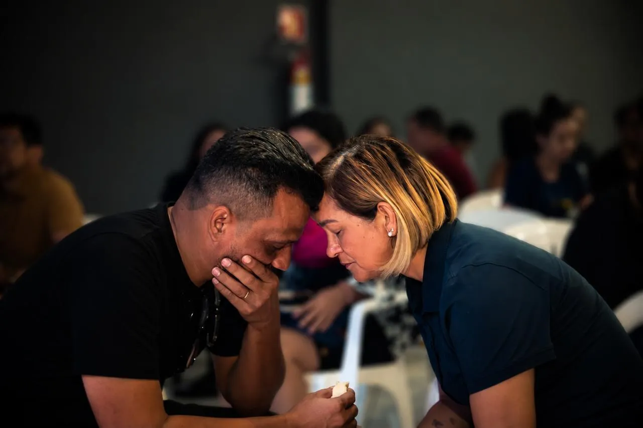 Casal de testa colada, emocionado, durante um encontro da Clínica Amor Redentor